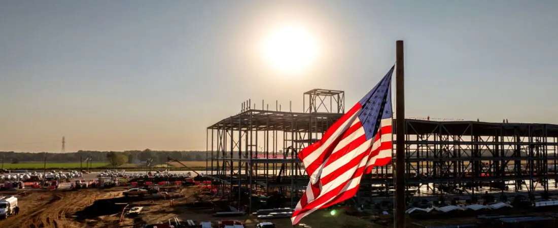 American flag flying above an Amazon data center construction site at sunset.